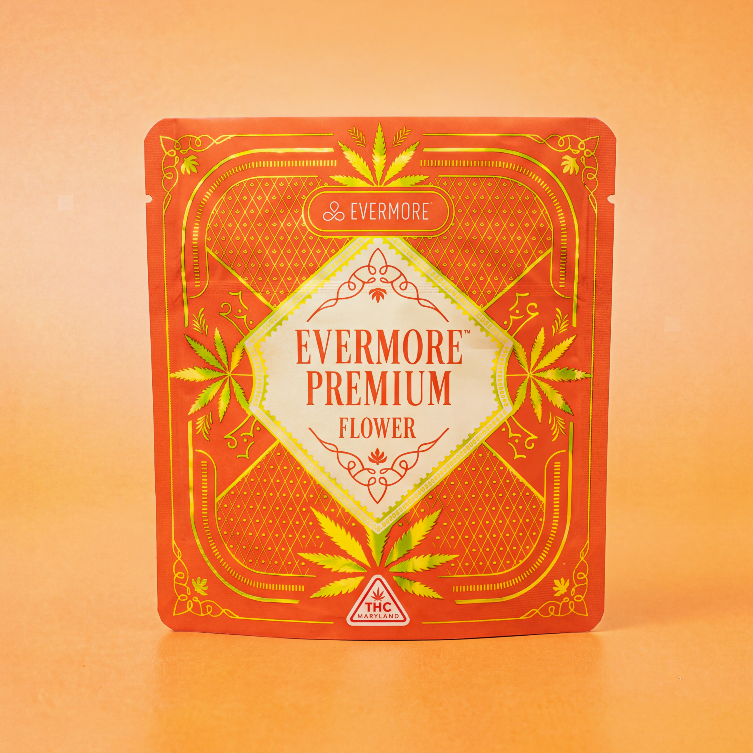 An orange and gold Evermore Premium Flower pouch standing upright against a warm orange background.